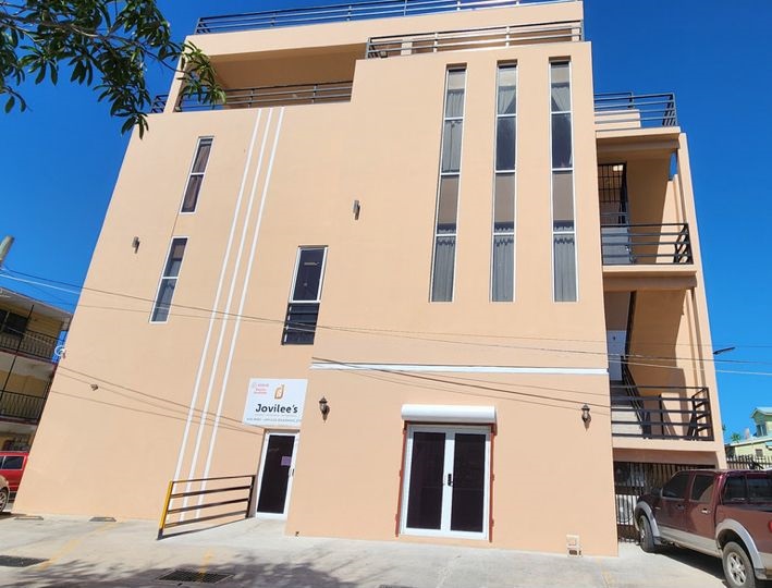 Outside of taller thin stucco building with decks at the top.